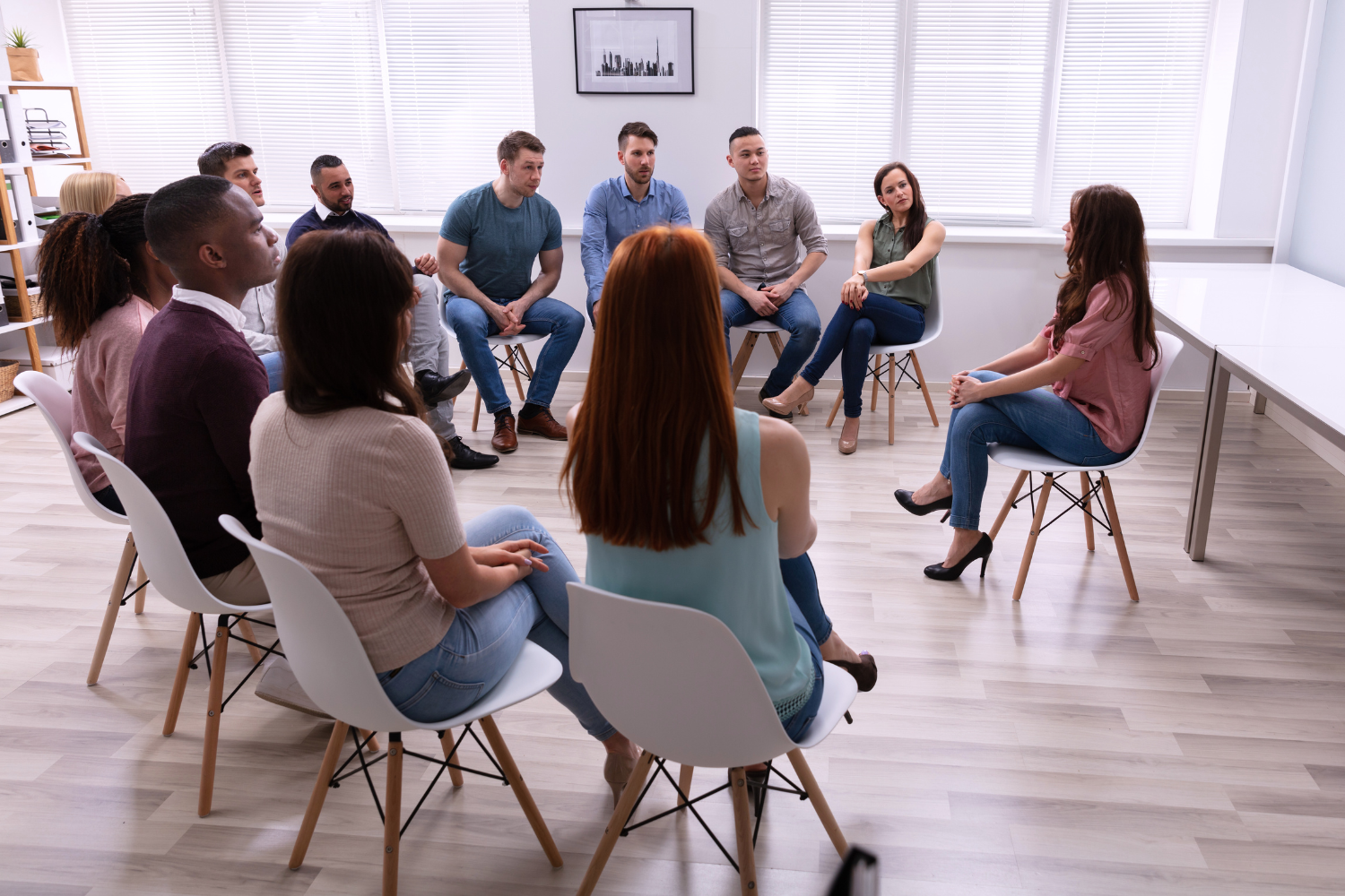 Group therapy session at Clarity Holistic Therapy featuring a diverse group of individuals seated in a circle, engaged in discussion and support in a comfortable, welcoming environment.